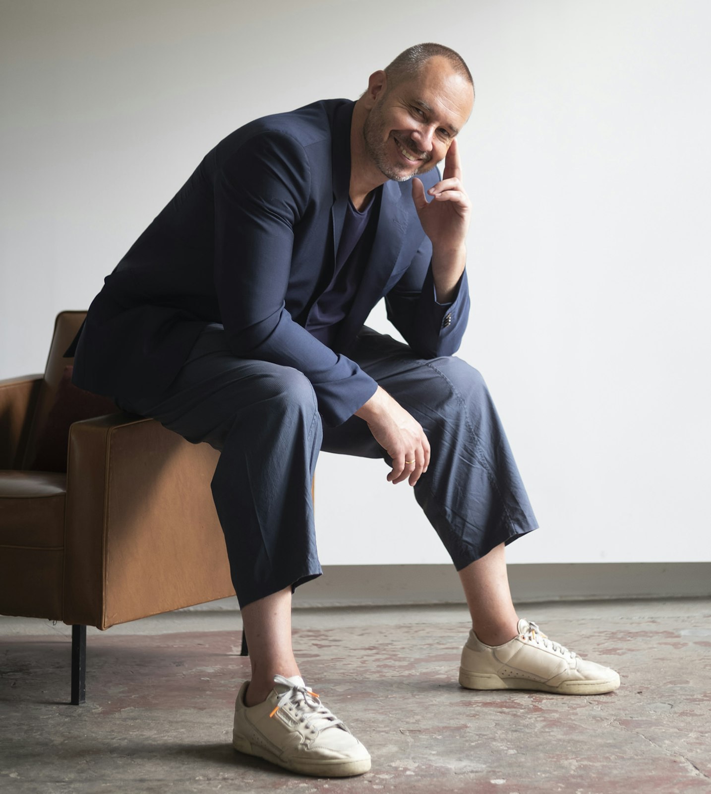 Portrait of designer Alain Gilles sitting on a chair